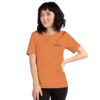 Female model wearing burnt orange shirt with "technology" and an illustration of how to sign technology is on the upper left chest