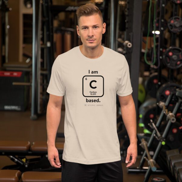 Male model in the gym wearing a cream "I am Carbon (as an element) Based" shirt. Atomic Hands logo on the bottom.