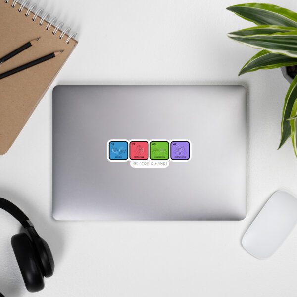 Laptop closed with ASL elements sticker on top (blue, red, green, purple per element). Pen, mouse, plant, and headphones slightly shown around the corners